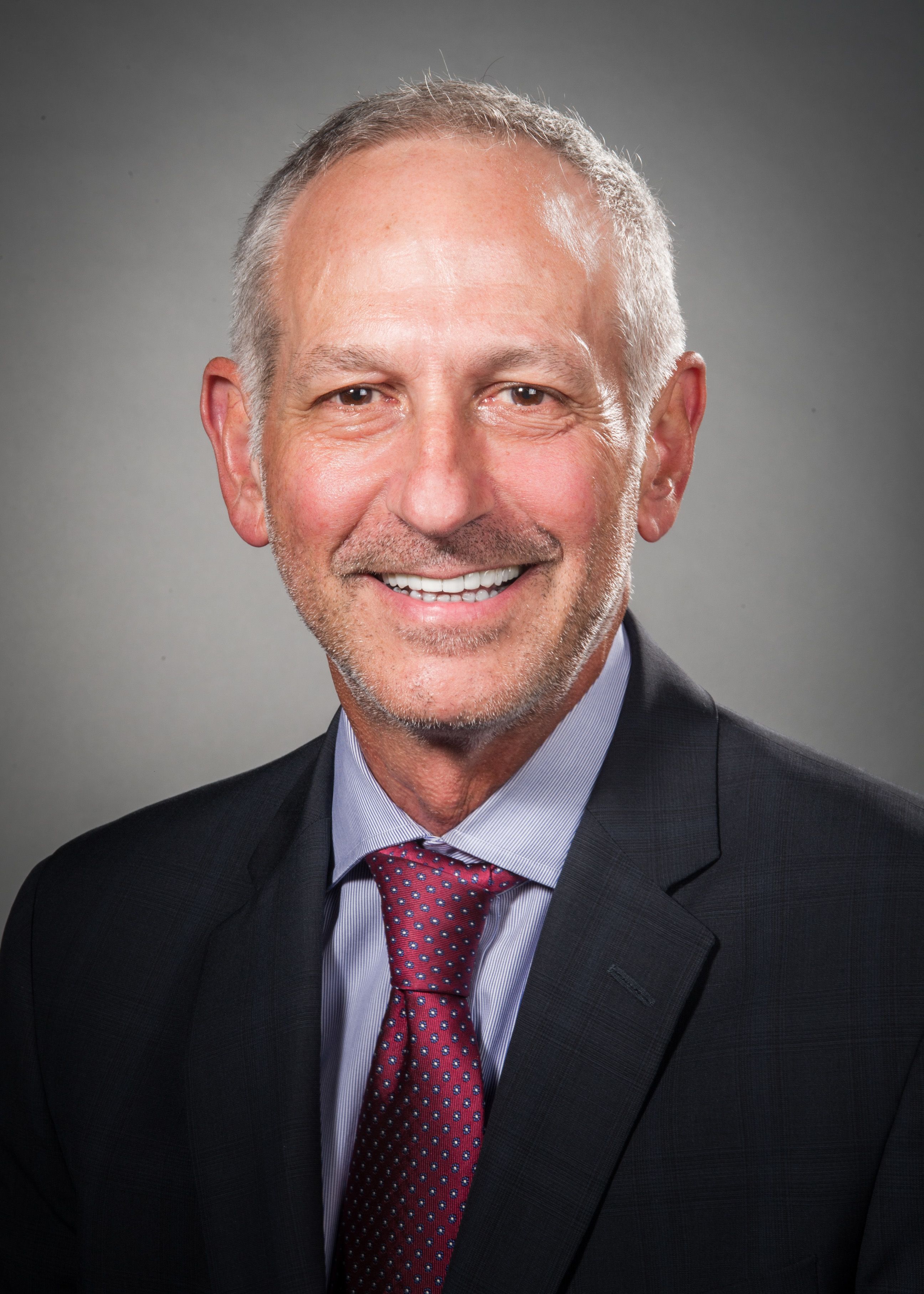Mark Schiffer, MD, wearing a red tie and a dark jacket